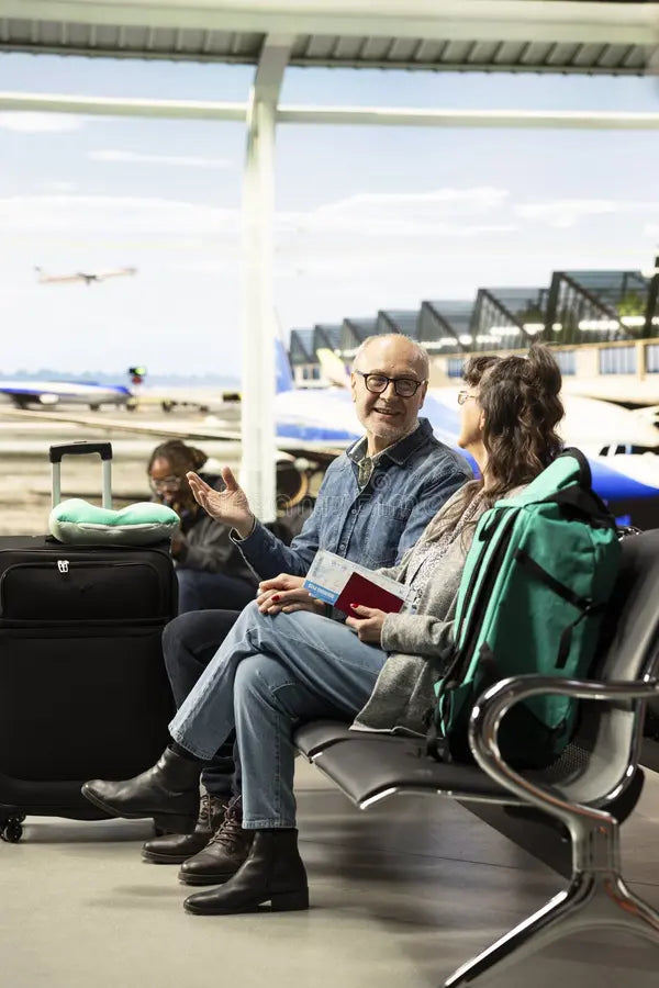 Older couple talking in an airport waiting area beside their luggage