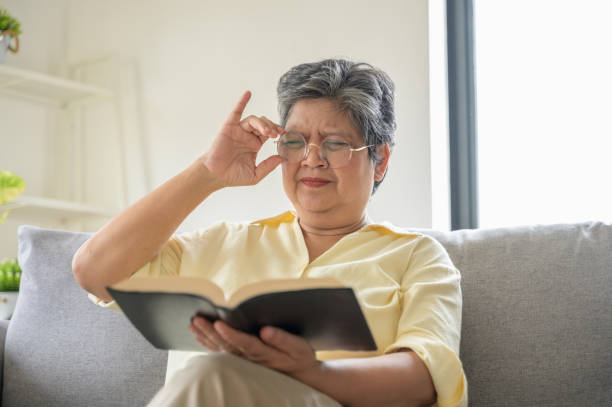 Older woman reading a book while adjusting her glasses