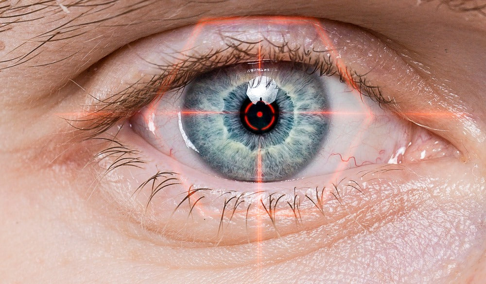 Close-up of a blue eye with red laser targeting lines
