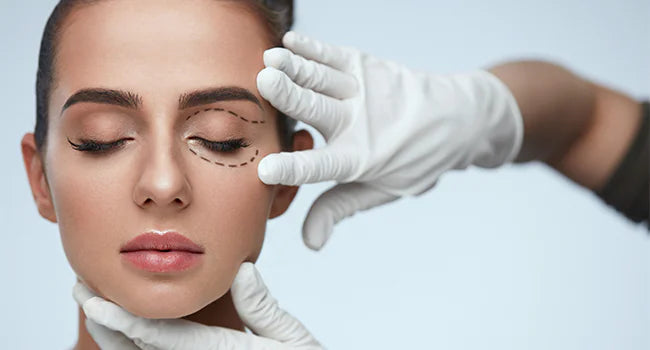 Woman with her eyes closed as gloved hands frame a dotted marking around one eyelid