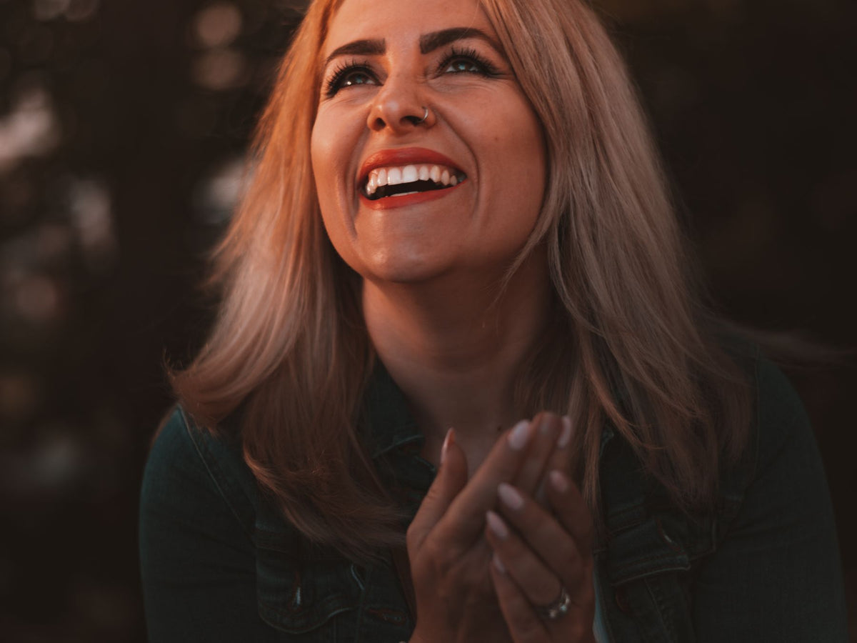 Smiling woman looking upward with her hands clasped