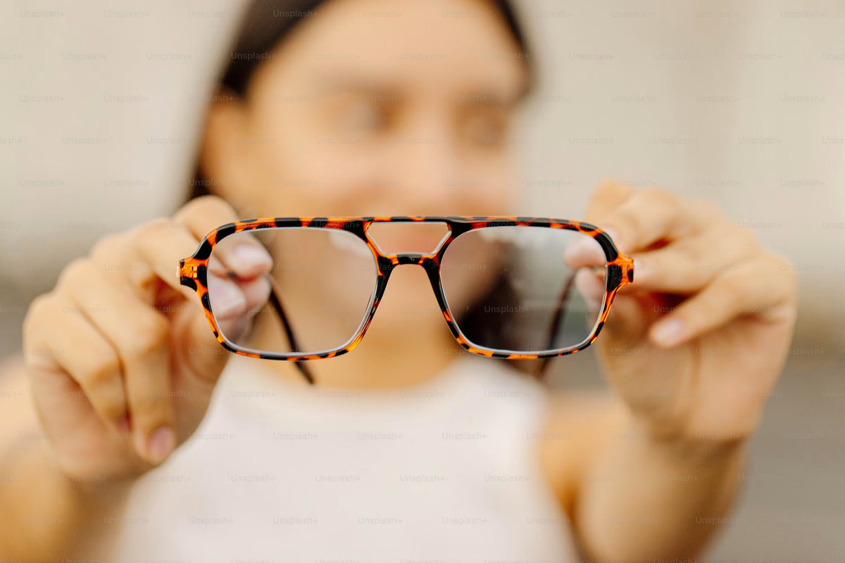 Person holding tortoiseshell eyeglasses toward the camera