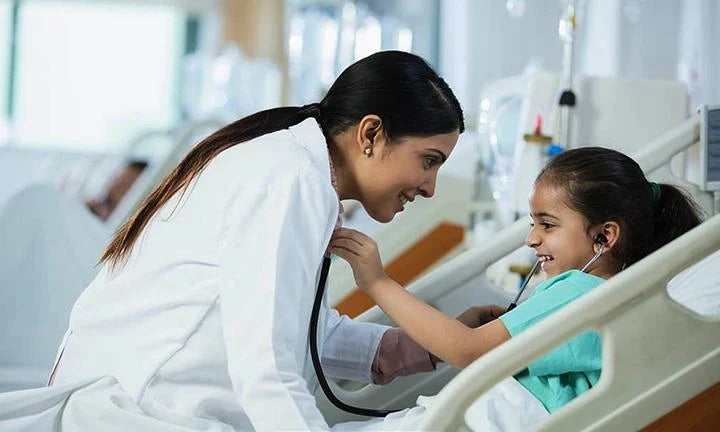 Female doctor and young patient smiling as the child uses a stethoscope